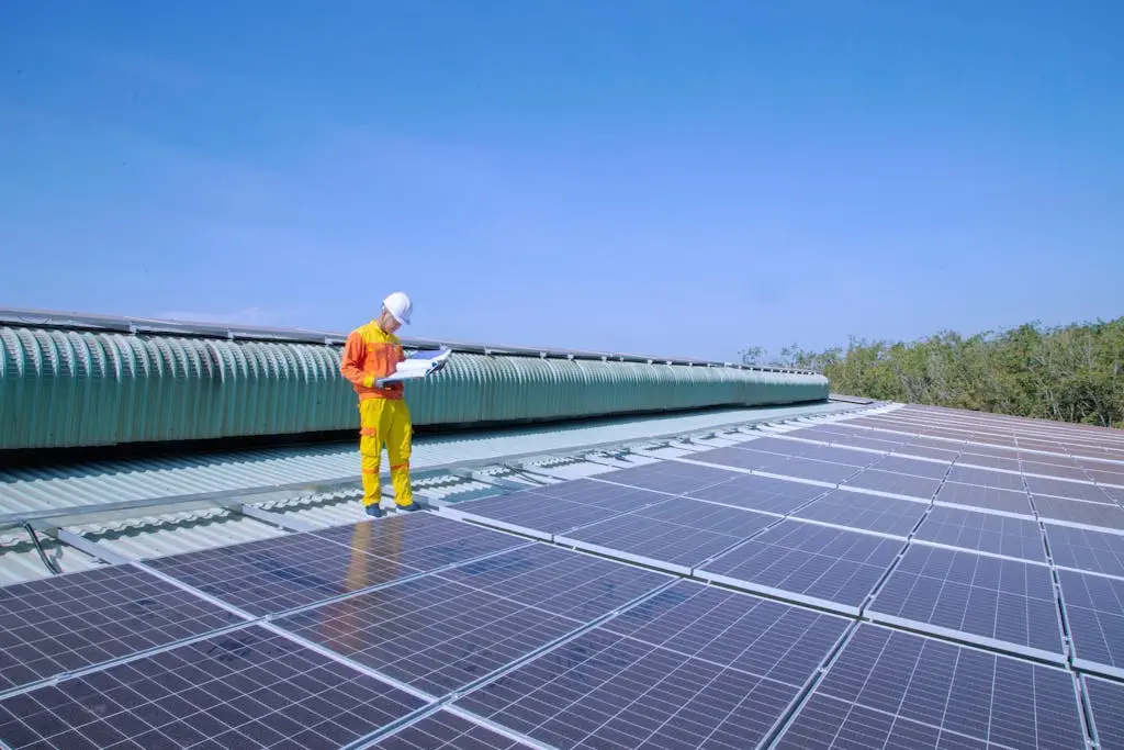 a solar technician inspects solar panels on a rooftop under a clear blue sky promoting renewable energy. 6961112 A solar technician inspects solar panels on a rooftop under a clear blue sky, promoting renewable energy.